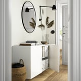 Wall-mounted cabinet with mirror, books, basket, and lamp.