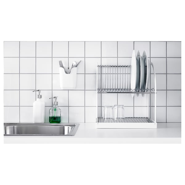 Kitchen sink with countertop, stainless steel, dish rack, green soap dispenser, white tiles.