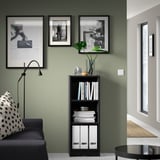 Black BILLY bookcase with books & decor, framed art, lamp, couch & pillow in green room with white tiles.