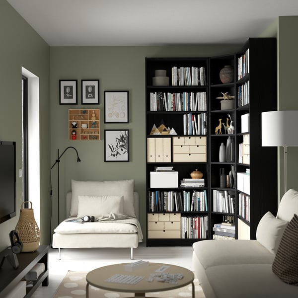 Modern living room with green BILLY bookcase, white sofa, and coffee table. Floor lamp creates cozy reading nook.