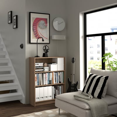 Modern living room with BILLY bookcase, couch, guitar, and urban view.