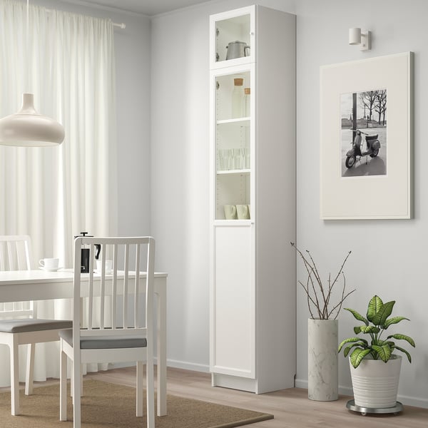 Modern dining area with BILLY bookcase, glass panels, and plant.