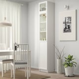 Modern dining area with BILLY bookcase, glass panels, and plant.