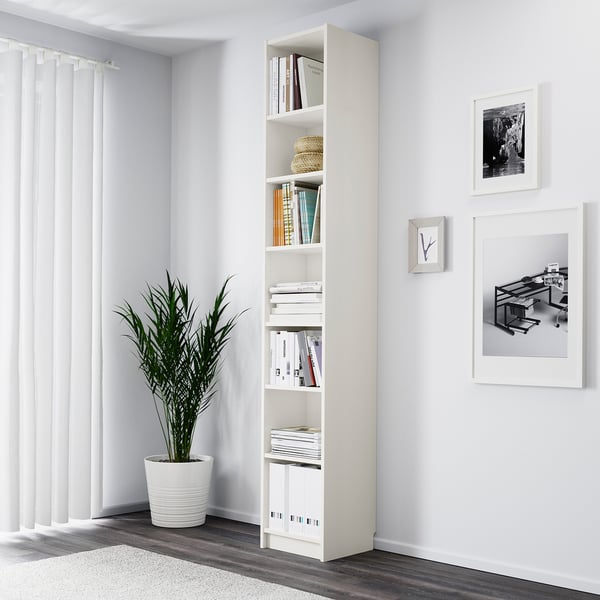 Minimalist room with BILLY white bookcase, tall plant, and wall art.