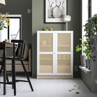 Modern dining area with white bamboo BILLY cabinet, black chairs, green walls, large window, and hanging plants.