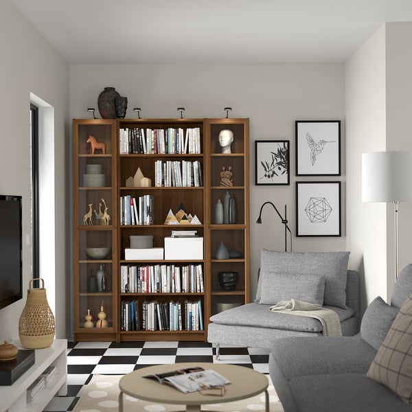 Modern living room with dark brown BILLY bookcase, books, art, sofa, & lamp on checkered floor.