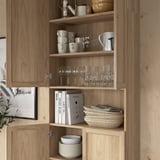 Wooden bookcase with glassware, mugs, books, and bowls neatly organized on shelves.