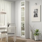 White BILLY bookcase with glass doors. Beside it, a dining set, framed picture, and plant. White curtains.
