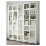 Large white BILLY bookcase with glass doors and open shelves, displaying books and decorations.