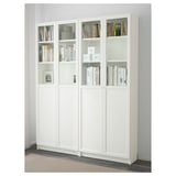 White bookcase BILLY with glass doors, displaying books on adjustable shelves, anchored to wall.