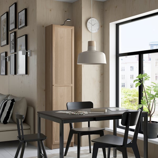 Modern living room with dining table, chairs, bookcase, sofa, clock, and lamp.