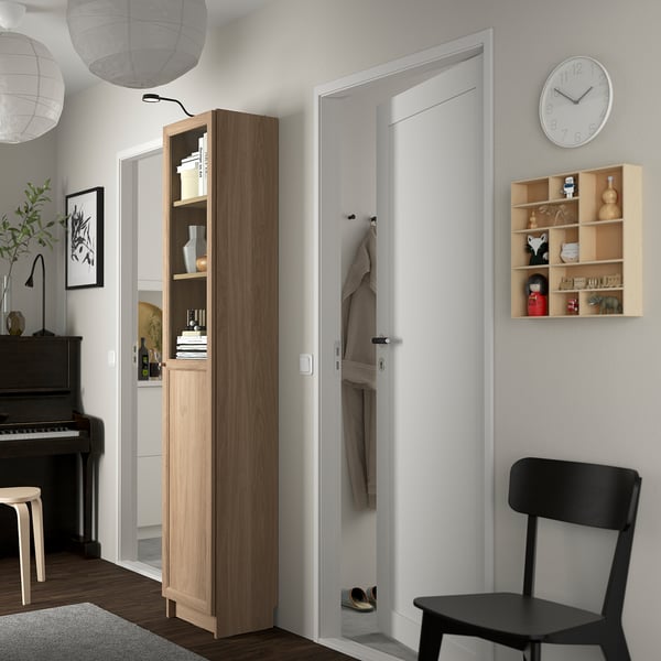 Modern living room with BILLY bookcase, closet, clock, chair, piano, decorations.