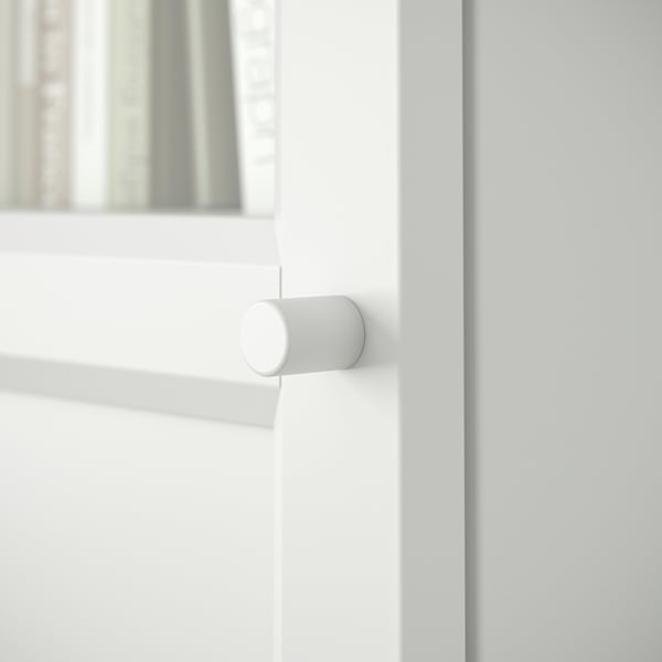 A white BILLY bookcase door hinge, round, on a white wooden door.