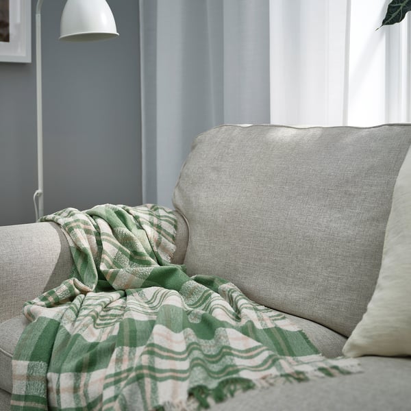 BISKOPSMÖSSA throw on sofa, green pattern, soft, fringed, covers pillow, near lamp.