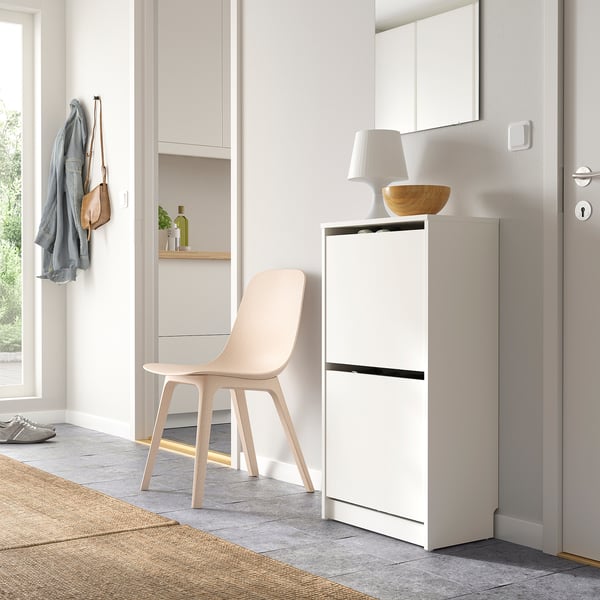 Modern hallway with white shoe cabinet, chair, and hanging storage.