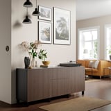 Modern living room featuring BJÖRKÖVIKEN oak sideboard, black pendants, art prints, and an orange sofa. Sideboard is central, tall, and sleek.