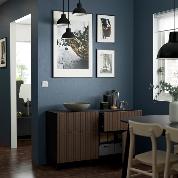 Dark oak kitchen sideboard with drawers, pendant lamps, photos, chair, and bowl.