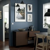 Dark oak kitchen sideboard with drawers, pendant lamps, photos, chair, and bowl.