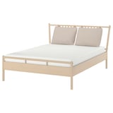 A BJÖRKSNÄS light birch wooden bed with beige pillows and a white mattress, featuring a classic headboard design.