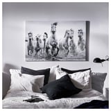Large black-and-white wall art of running horses above bed with white comforter and multiple pillows.
