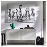 Horse artwork above cabinet with green vase and black bag.