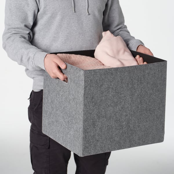Person holding a gray felt box with handles, designed to fit kallax shelving.