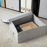 Gray BLÄDDRA felt storage box on shelf, holding notebook and cd case, smaller than books.