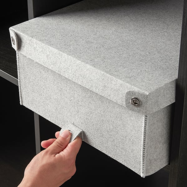 Image description: hand opening a grey felt storage box, likely BLÄDDRA, designed to hide items neatly. Fits into kallax shelving.