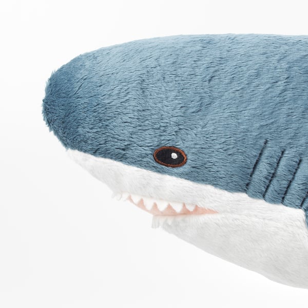 Soft blue shark plush toy with white teeth, cute and inviting, perfect for cuddling.