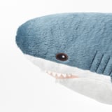 Soft blue shark plush toy with white teeth, cute and inviting, perfect for cuddling.