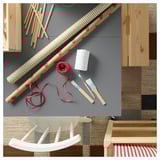 Scandinavian-style craft room: colorful wrapping paper, string, brushes on grey rug; red-and-white striped chair.