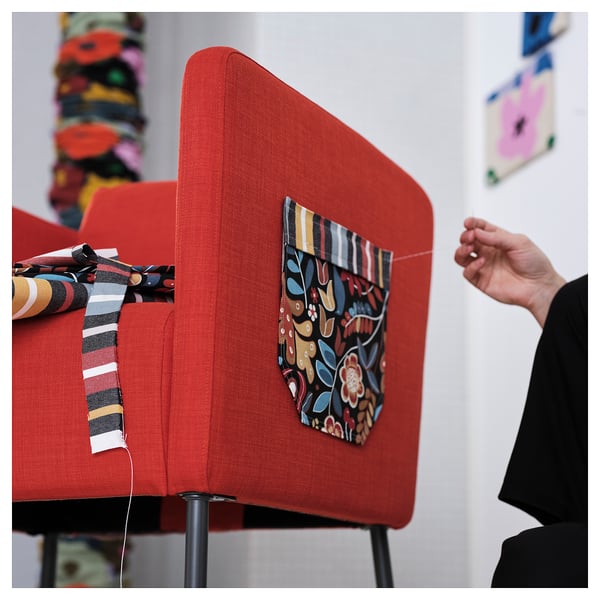 A person sits at a red upholstered desk with fabric decorations and a striped ribbon.