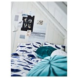 Cozy bedroom with blue whale bedding, teal pillows, wall art, and a plant.