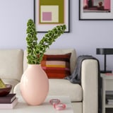 Pink ceramic vase BLODBJÖRK with green plant branches on table.