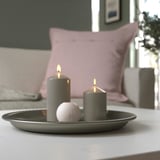 Gray candle dish with two lit candles and a decorative stone, enhancing room ambiance.