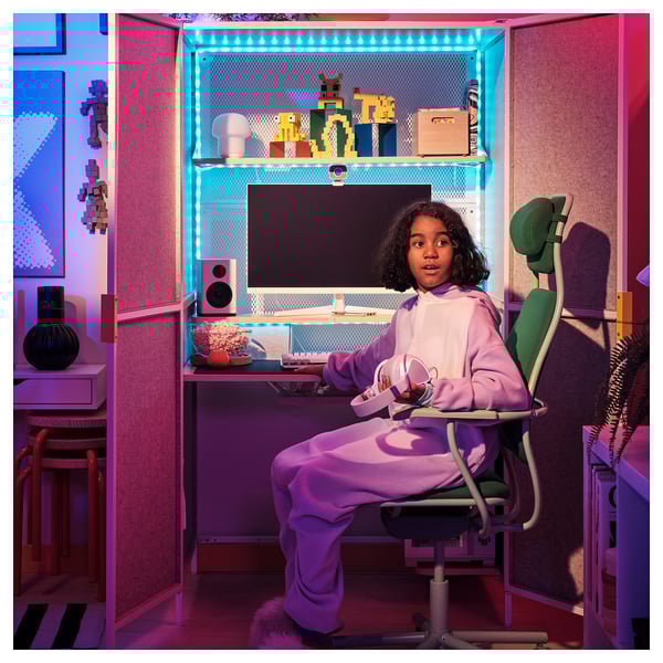 Girl at BRÄNNBOLL gaming desk with monitor, speaker, gear, adjustable shelves, hidden chair, felt material.