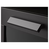 Modern black handle on sleek, dark furniture; smooth edges.