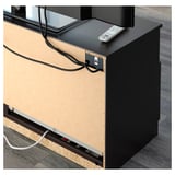 Black tv stand with visible cable management and remote control.