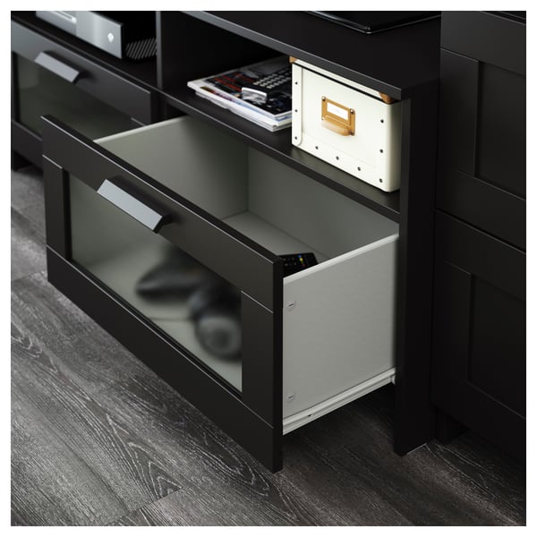 Black tv stand with glass doors; two open drawers revealing remote and boxes, adjustable shelves, and cable outlets.