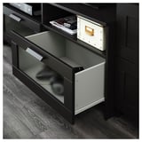 Black tv stand with glass doors; two open drawers revealing remote and boxes, adjustable shelves, and cable outlets.