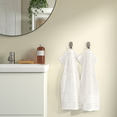 Two towels hang on hooks beside a sink with a mirror above.