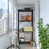 Balcony with BROR black shelving unit. Holds pots, tools, and bags. Near bike and green plant. Fits below tall city windows.