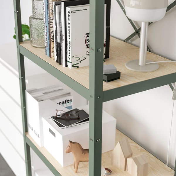 Modern green metal shelf holds books, boxes, and lamp, sturdy and durable.
