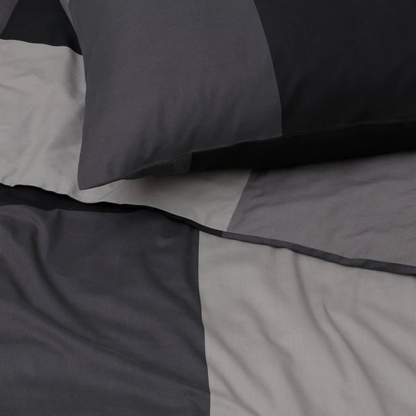 Soft, folded gray bedding set with smooth fabric, featuring sleek black trim, neatly arranged.