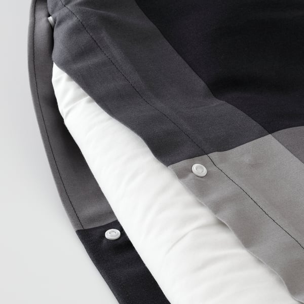 Close-up of grey BRUNKRISSLA duvet cover with plastic press-stud closure and textured fabric.