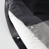 Close-up of grey BRUNKRISSLA duvet cover with plastic press-stud closure and textured fabric.