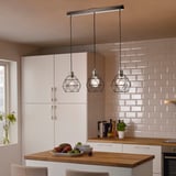 Modern kitchen with white BRUNSTA pendant lamps above wooden island, holding fruit bowl. Light, geometric design complements clean, minimalist decor.