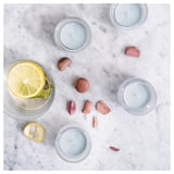 Four blue candles, wooden pieces, and a lemon slice on marble. Modern & minimalist design.
