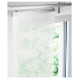 A sheer white panel curtain, mounted on brackets, softens light in a window, offering a clean, layered look.