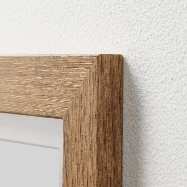 Close-up of lightweight, light brown wooden frame corner. Shows smooth texture and clean finish against white wall.